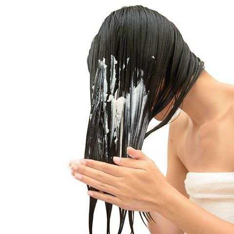 A girl applying conditioner to wet hair for nourishment and shine.