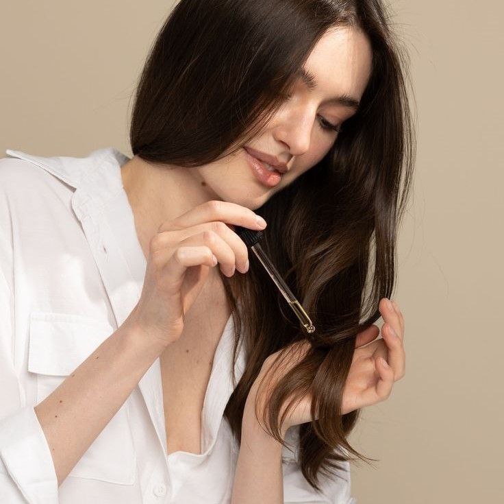 Applying hair oil to moisturize dry ends.