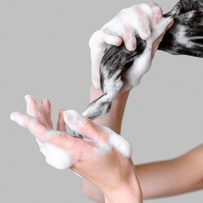 The process of applying a care product to clean hair.